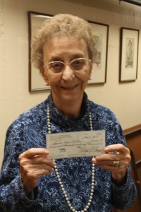 Marcie Leitzke, the last active founding member of the Shawano Area Writers, holds up a $77,090.32 check from the estate of George Putz that the group received in October. Putz’s will designated that the money should go toward reviving the group’s annual writing contest. (Photo by Lee Pulaski)
